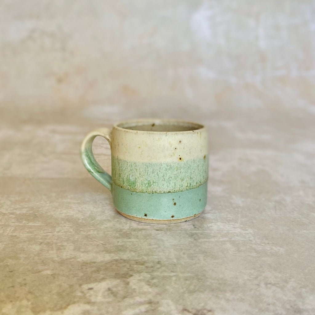 Small ceramic mug with a speckled off-white top, a light green middle band, and a darker green bottom band.