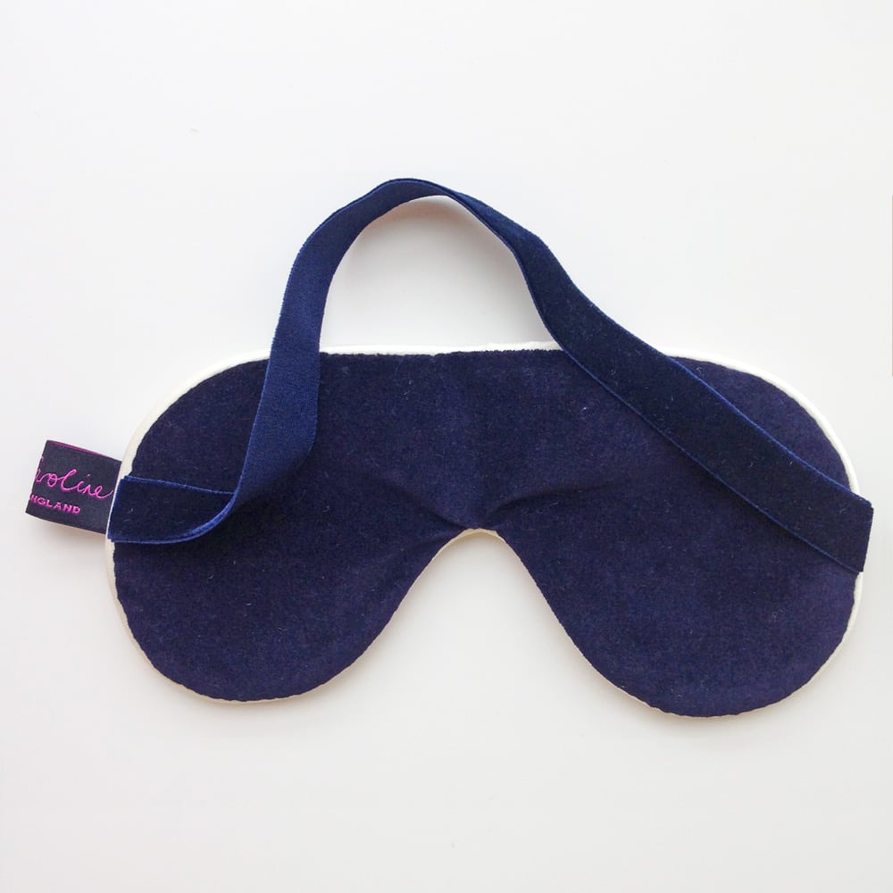 Navy blue velvet sleep mask with an off-white silk lining and adjustable headband.