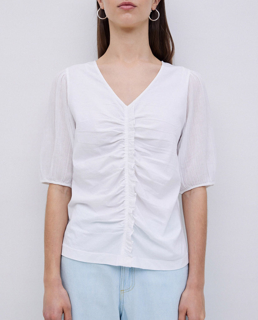 White v-neck, short-sleeve top with ruched center detail and sheer sleeves.