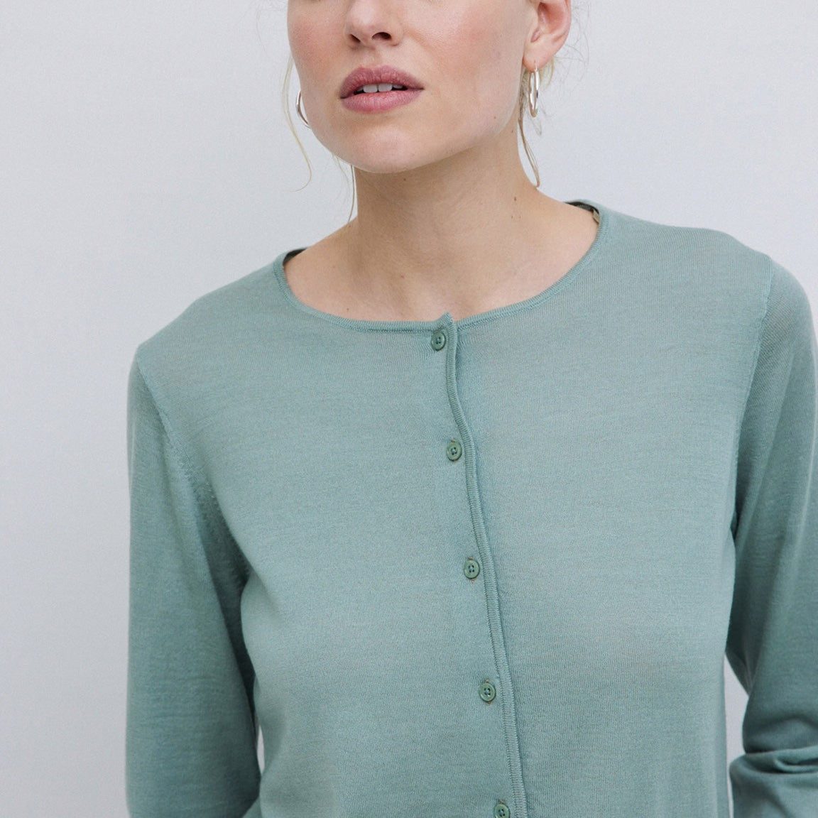 Sage green merino wool cardigan with a round neckline and button front closure.