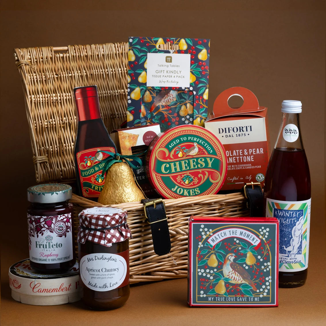 Gourmet gift basket with wine, cheese, and other snacks on a brown background