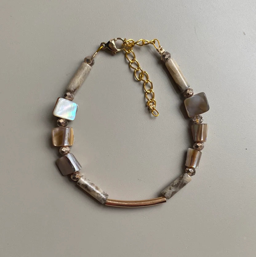 Bracelet with beads and gold chain on a light gray background