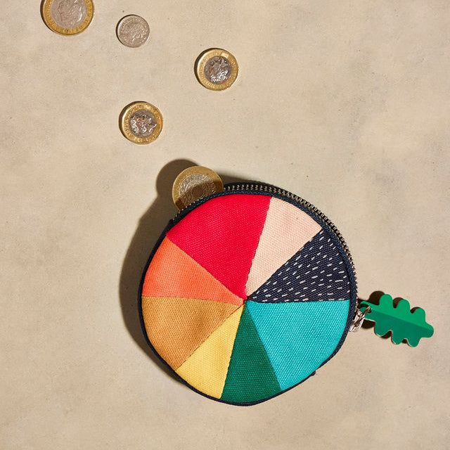 Colorful round coin purse with coins on a beige background