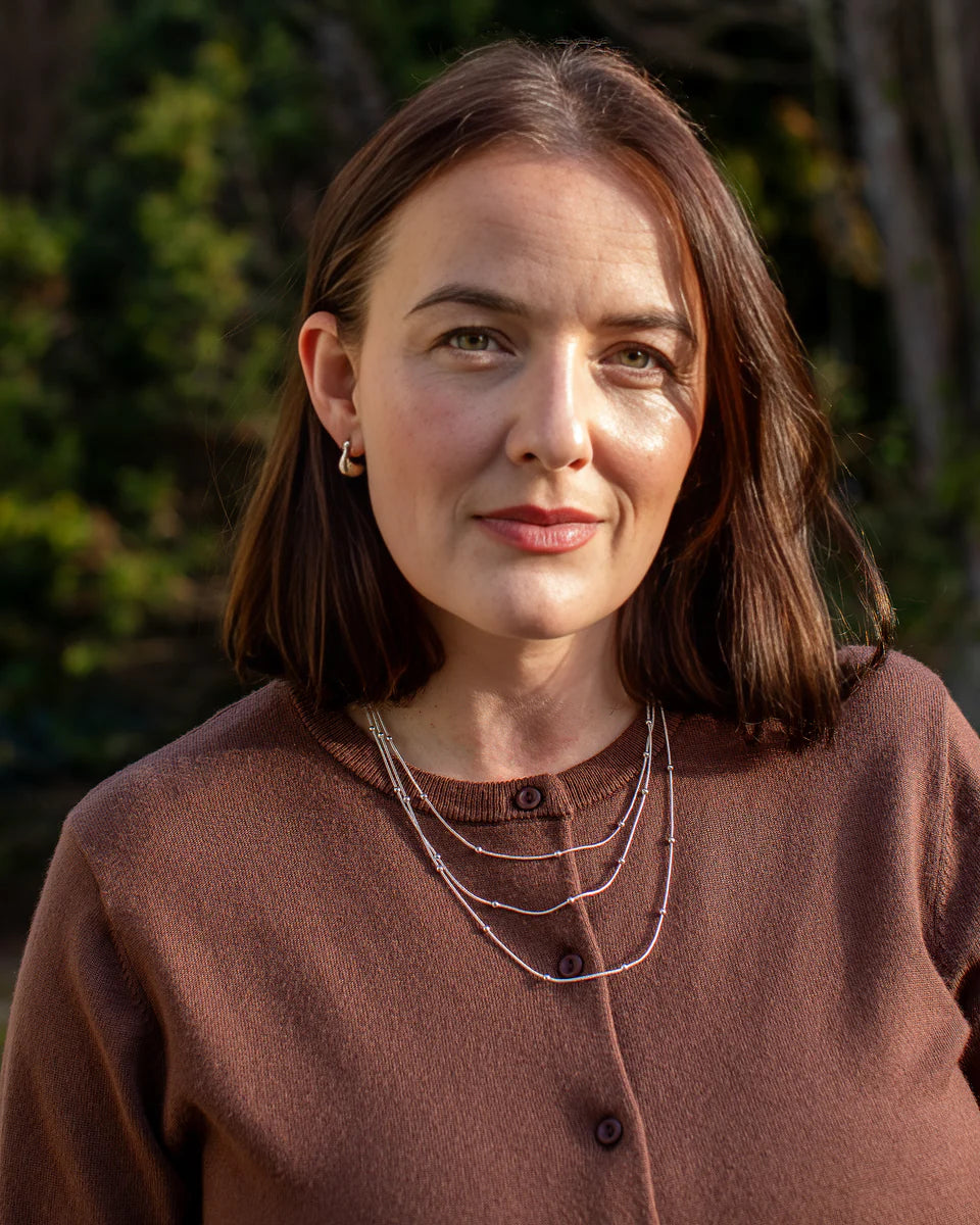 Woman wearing a brown sweater with a blurred natural background