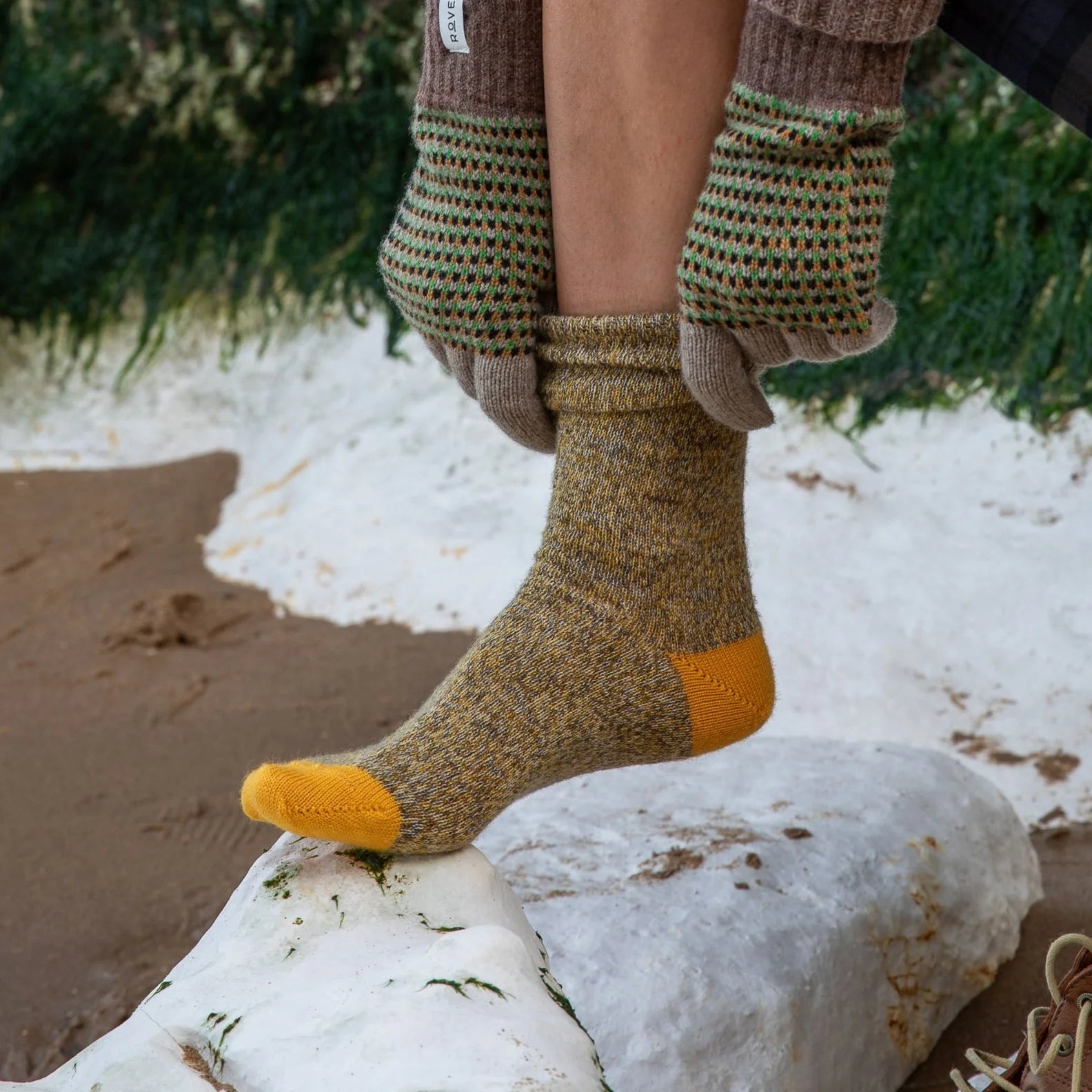 A speckled mustard-yellow and grey wool sock with a yellow heel and toe.