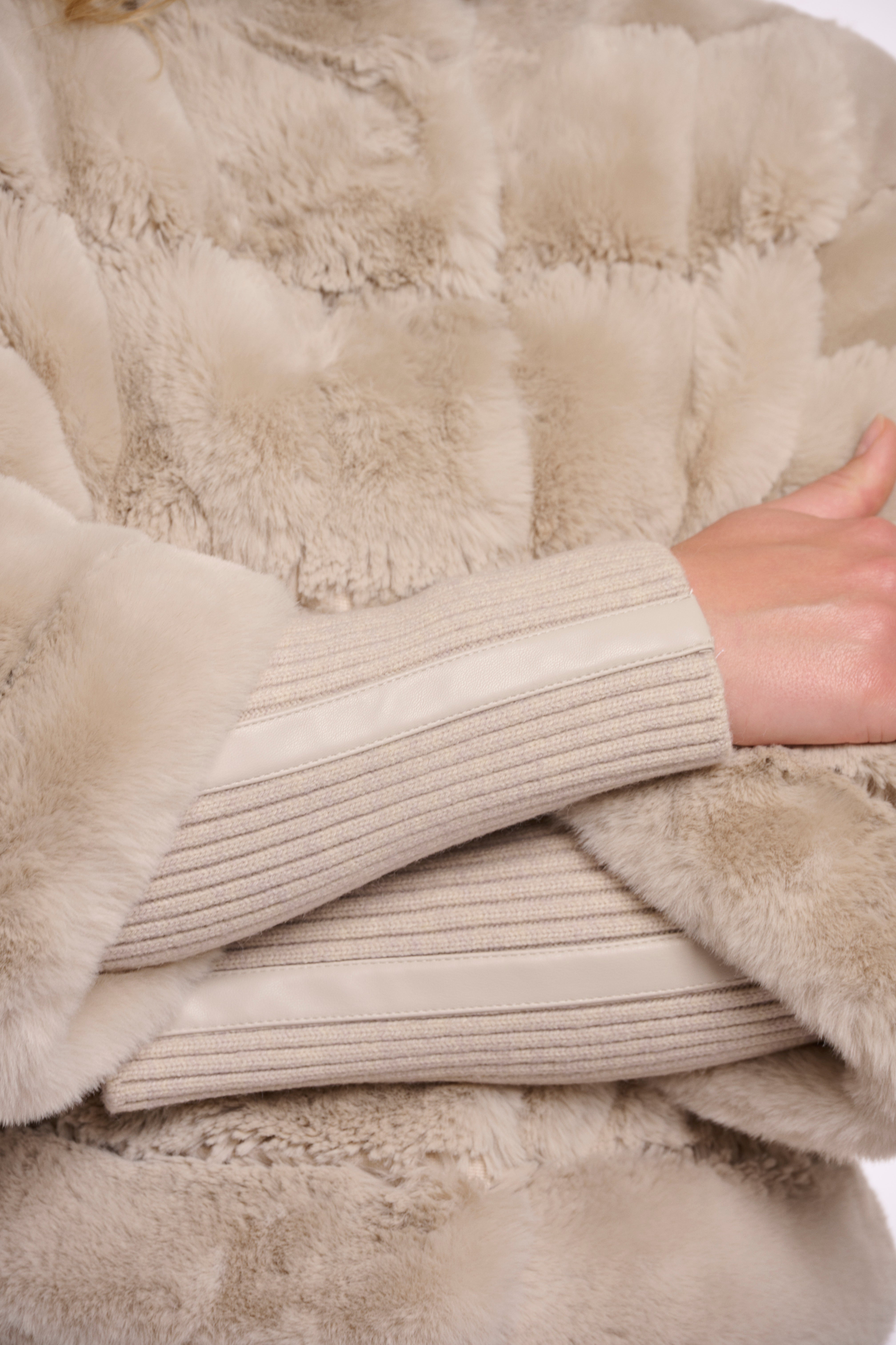 Close-up of a person wearing a beige sweater with a fluffy texture.