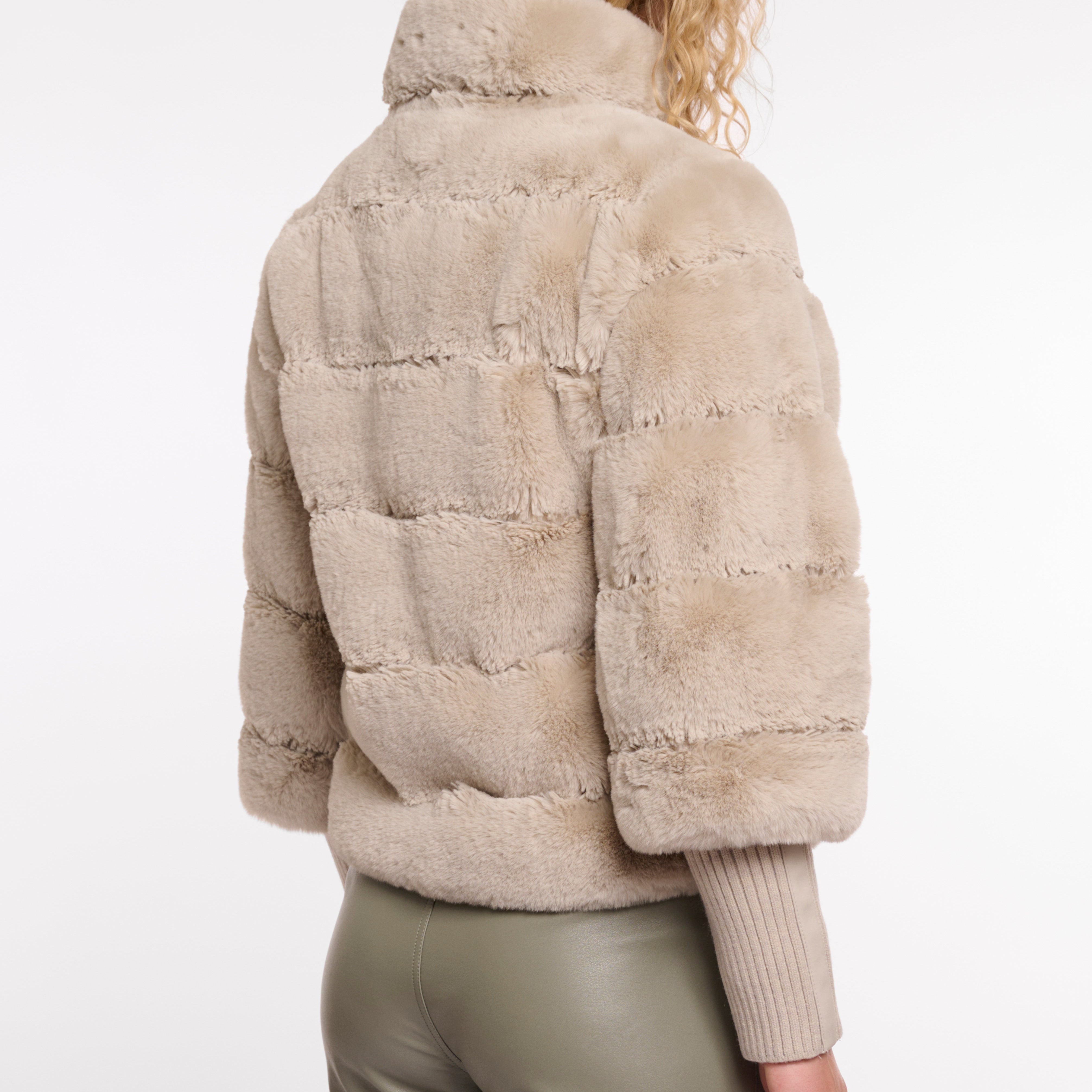 Beige puffer jacket worn by a person on a white background
