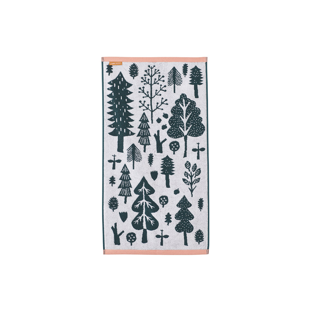 Patterned towel by Donna Wilson featuring dark green trees on a white background, trimmed with peach.
