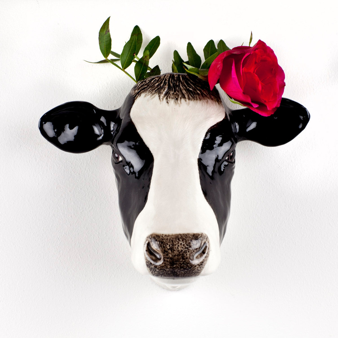 Black and white ceramic cow head wall planter with a red rose and greenery.
