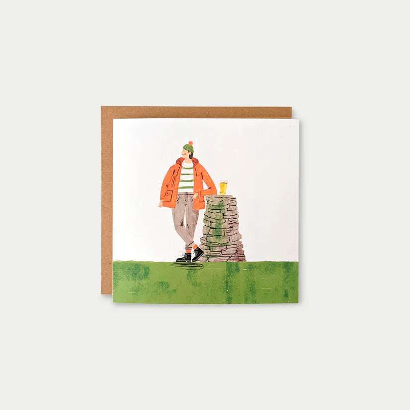 Illustrated greeting card featuring a person in an orange jacket leaning against a stone cairn, holding a drink.