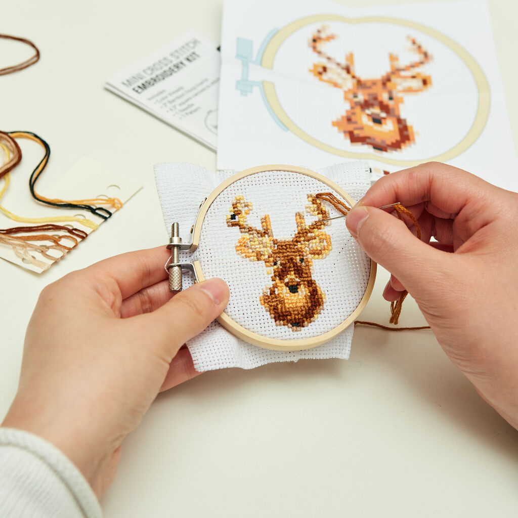 Mini cross-stitch embroidery kit depicting a deer's head, partially completed in brown and beige threads on a white fabric