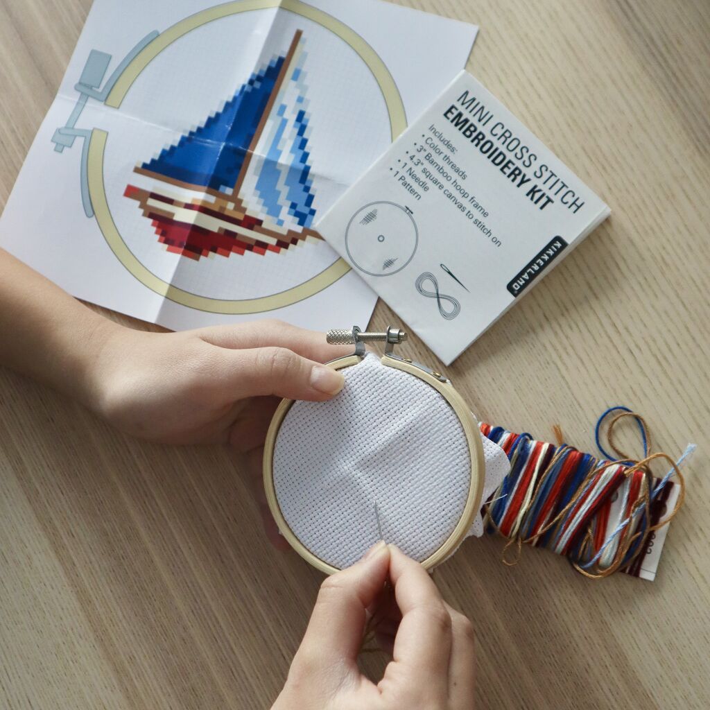 Mini cross-stitch embroidery kit with sailboat pattern, showing partially completed project in a bamboo hoop.