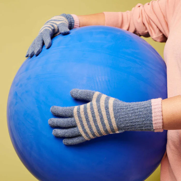 Large blue exercise ball held by hands wearing horizontally striped grey and beige gloves.