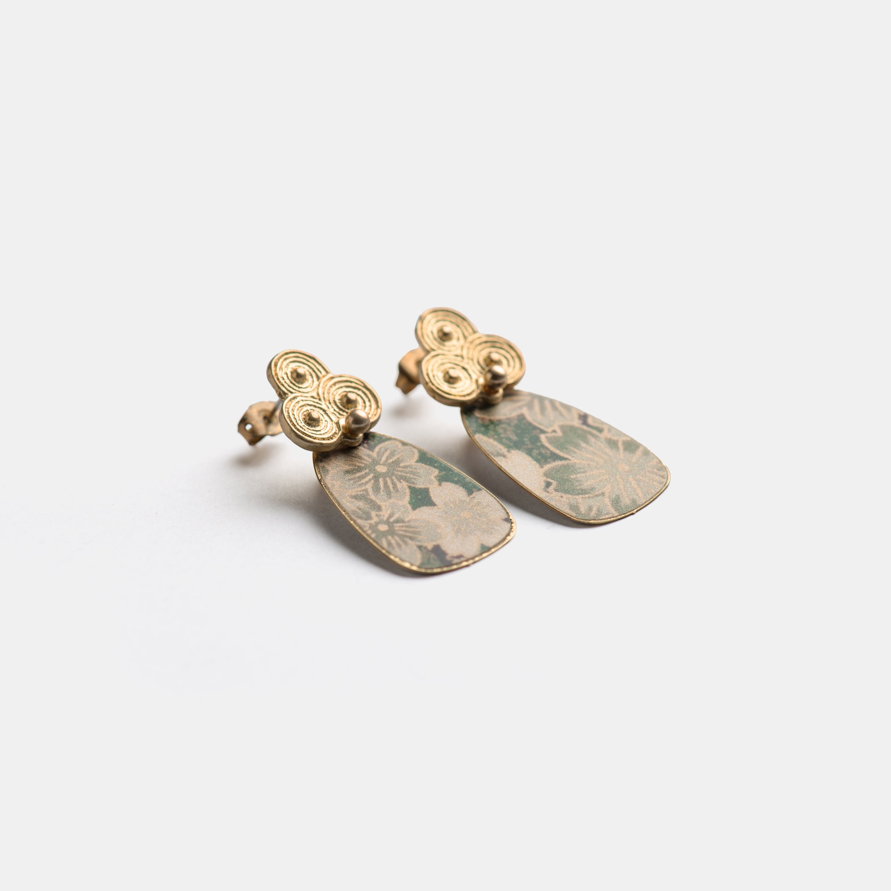 Pair of gold and green earrings.  Rectangular green floral patterned dangles with gold swirl detailing at the top.