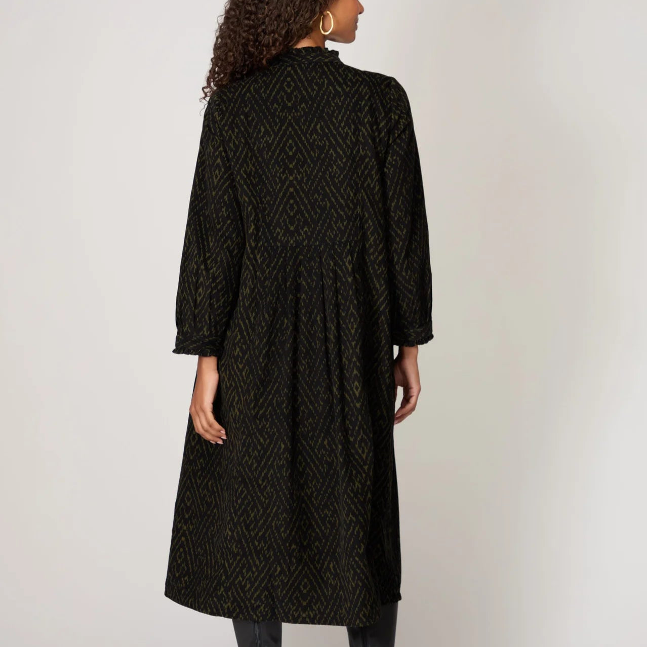 Woman wearing a black patterned dress against a white background