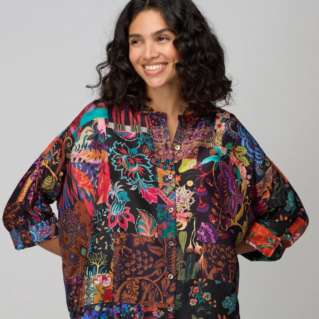 Woman wearing a colorful patterned shirt against a plain background