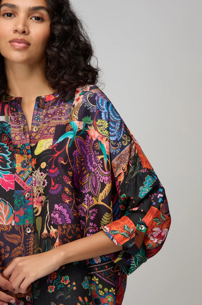 Woman wearing a colorful patterned shirt against a plain background