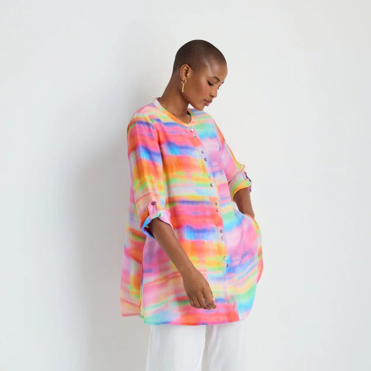 Person wearing a colorful striped shirt and white pants on a white background