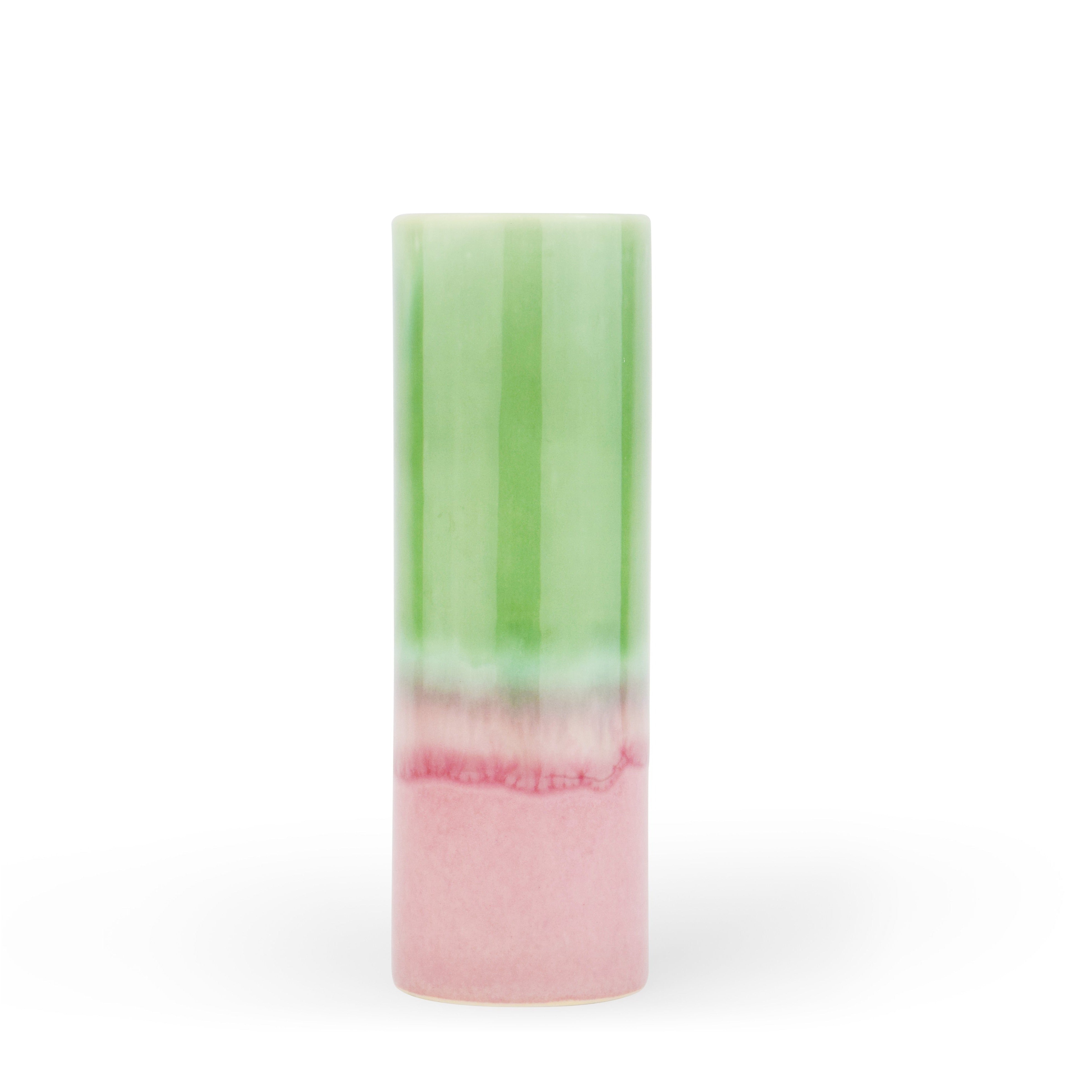 A cylindrical ceramic vase with a gradient of green to pink color.