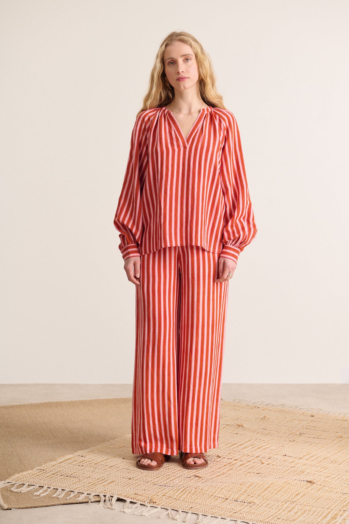 Red and pink striped wide-leg pants and matching long-sleeve blouse.  The top has a V-neck and balloon sleeves.