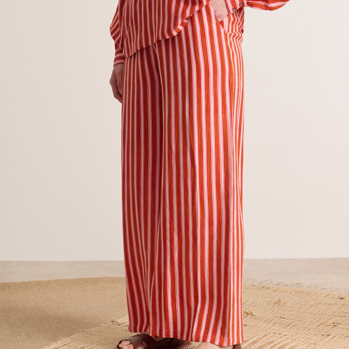Wide-leg pants with vertical stripes in red, pink, and orange.