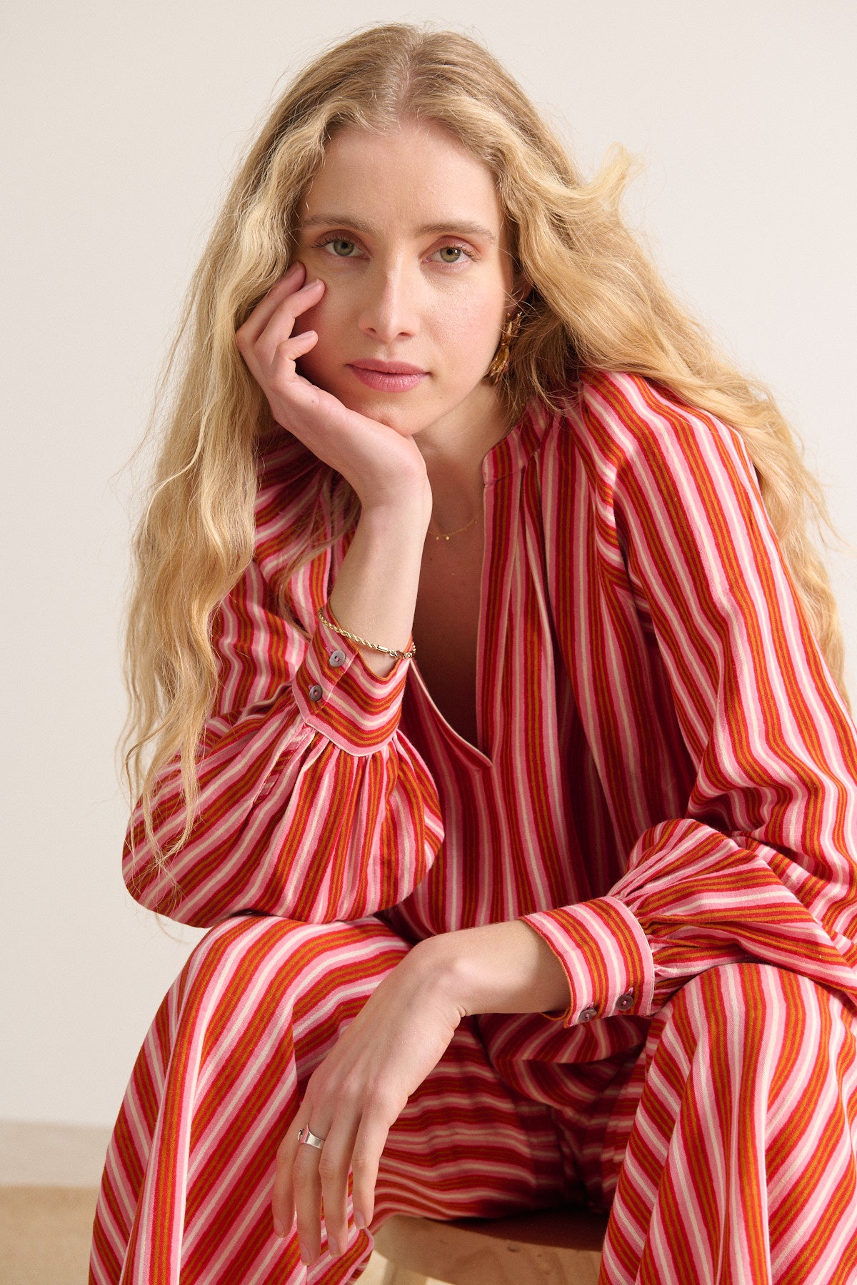 Red and pink striped jumpsuit with long sleeves and a V-neck.