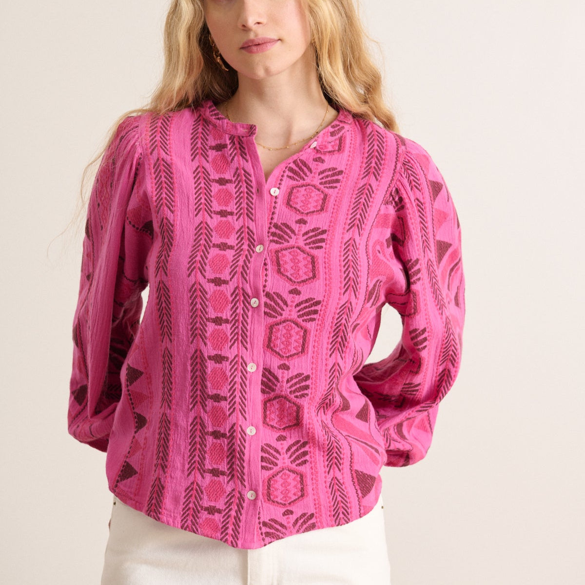 Pink long-sleeve button-up blouse with a geometric embroidered pattern in maroon.