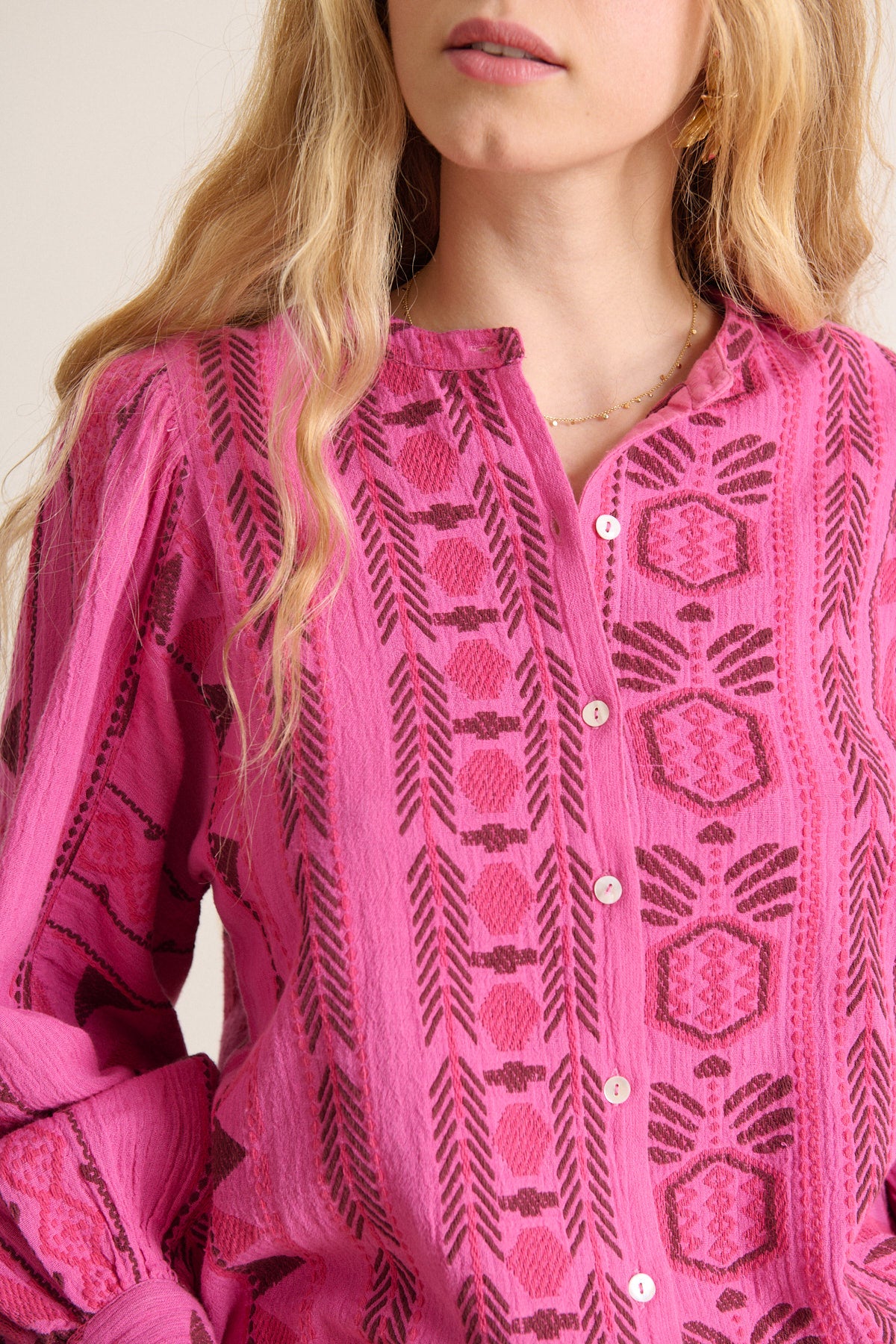 Pink embroidered button-up shirt with long sleeves and a geometric pattern in a darker pink.