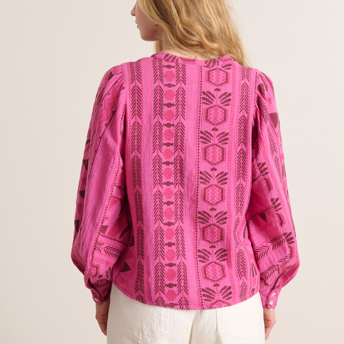 Pink long-sleeve blouse with a dark pink geometric embroidered pattern.  Puff sleeves and a relaxed fit.