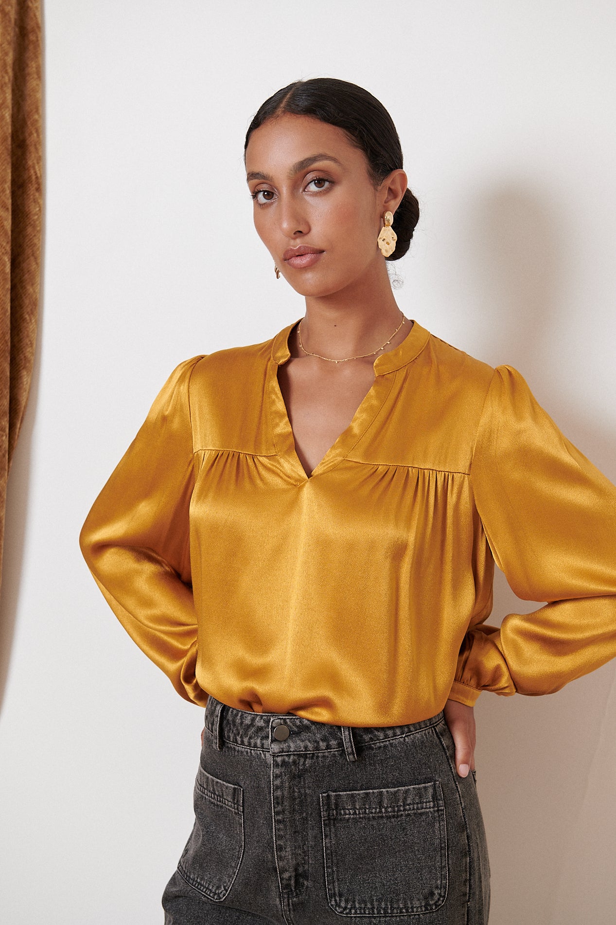 Mustard yellow satin blouse with long sleeves and a V-neck.