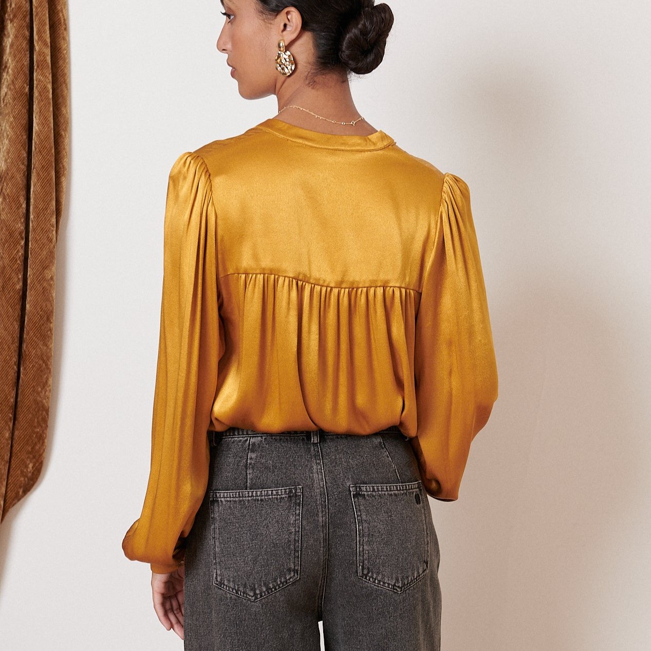 Mustard yellow satin blouse with long sleeves and a gathered waist.