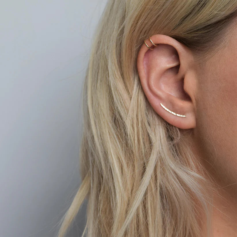Gold ear crawler earring with hammered texture.