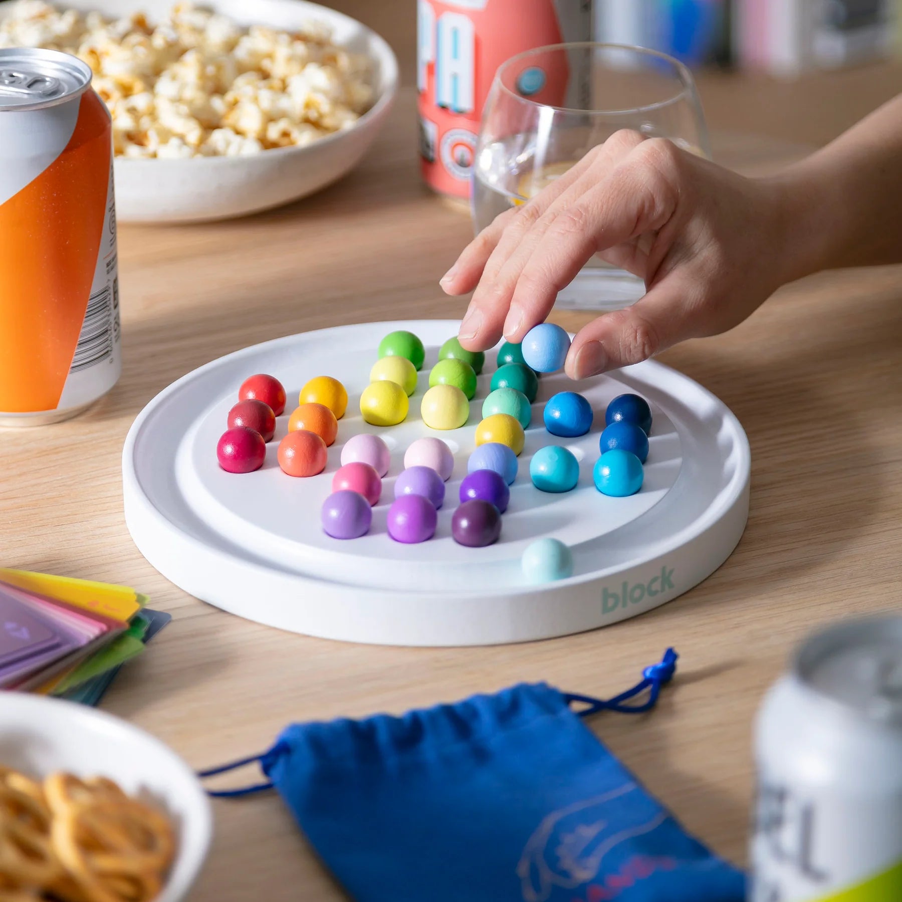 Colorful magnetic block game on a wooden table with snacks and drinks.