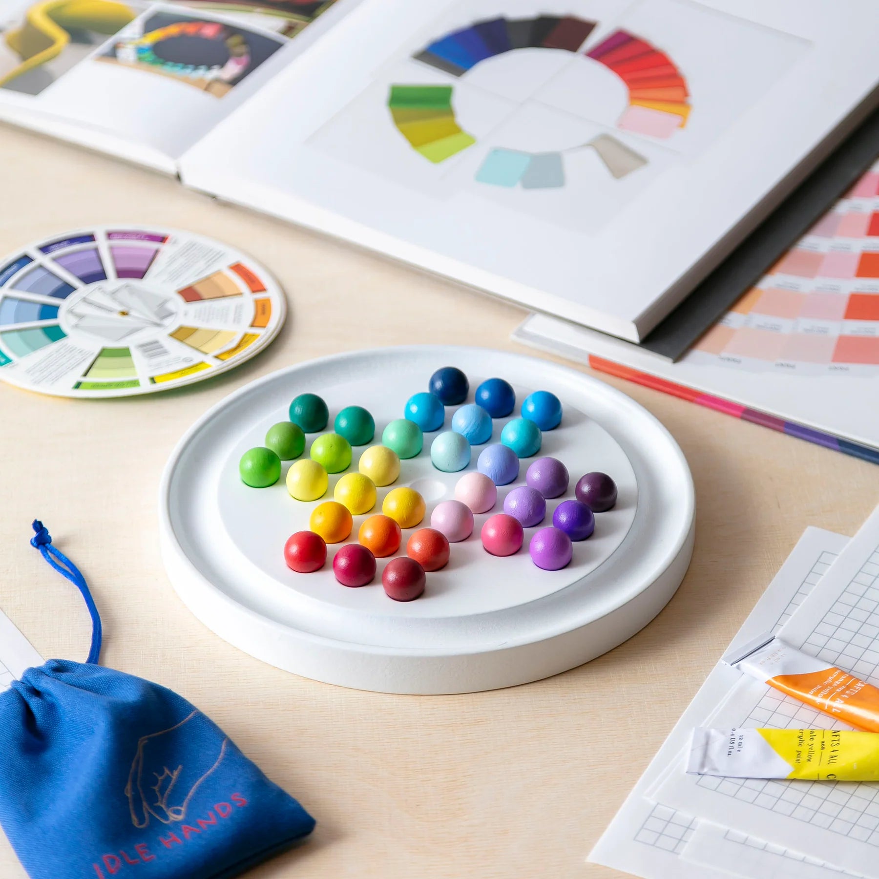 Colorful beads on a circular tray with a color wheel and design books in the background.