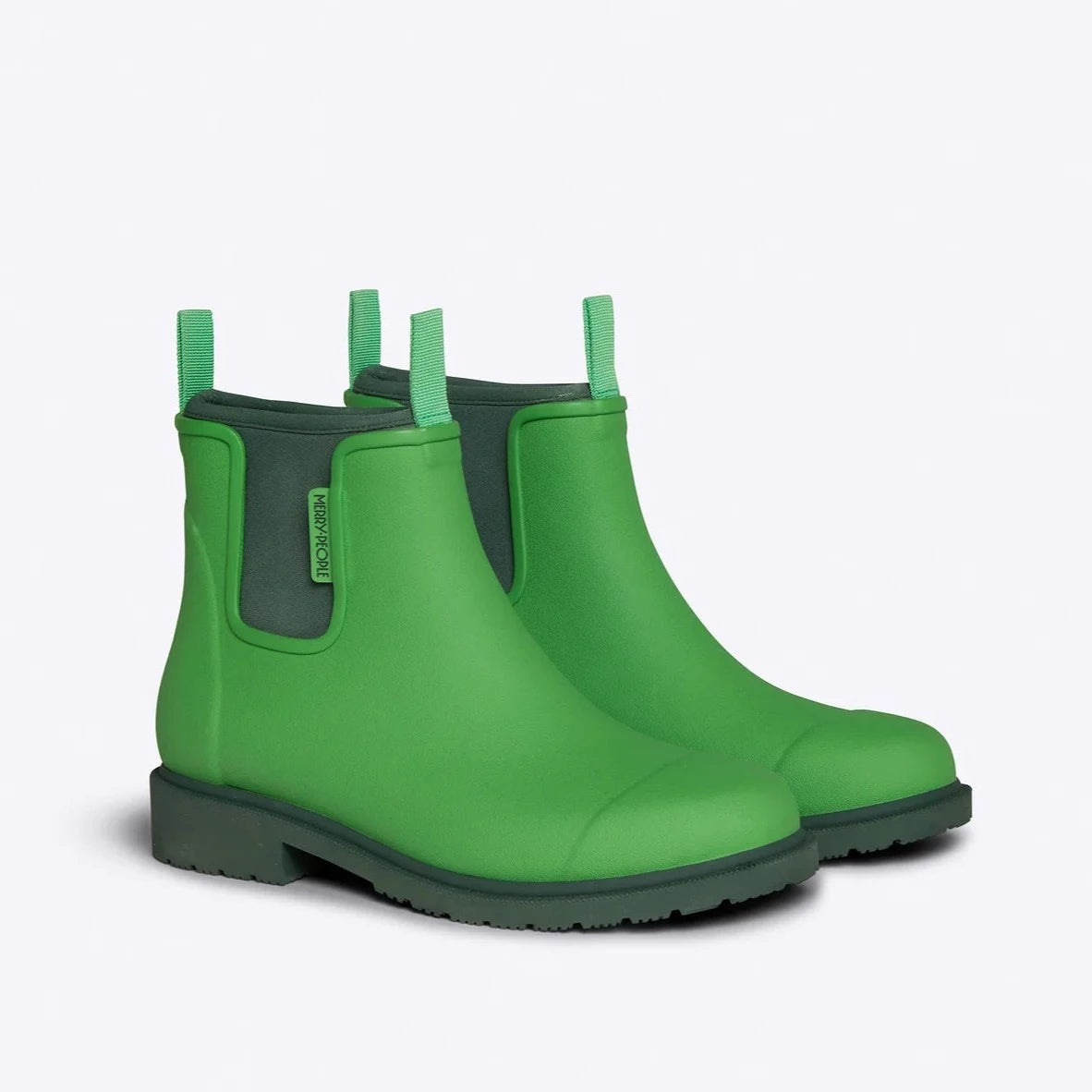 Pair of bright green rubber Chelsea boots with dark green soles and a subtle brand label.