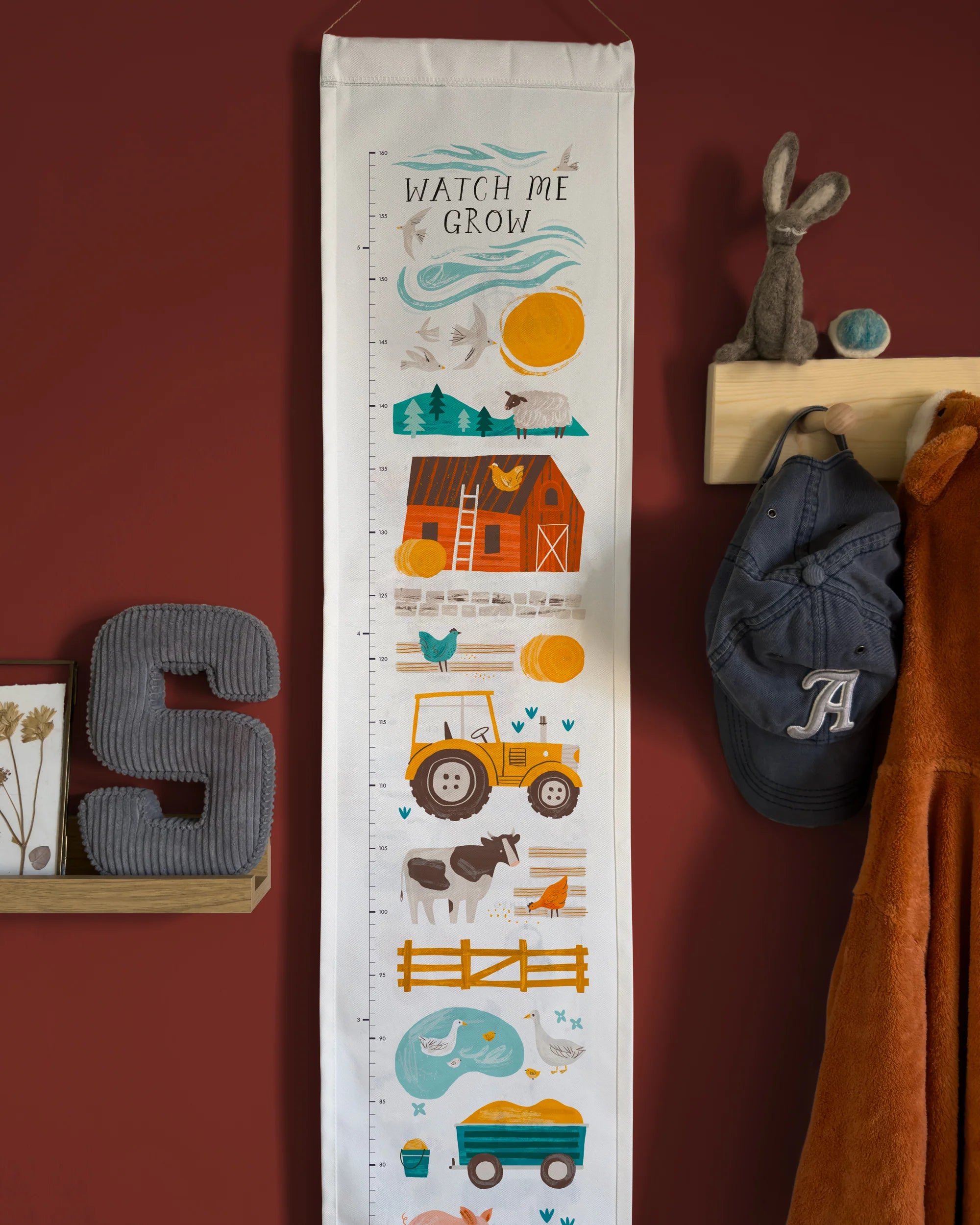 Growth chart with farm-themed illustrations on a red wall with decorative items.