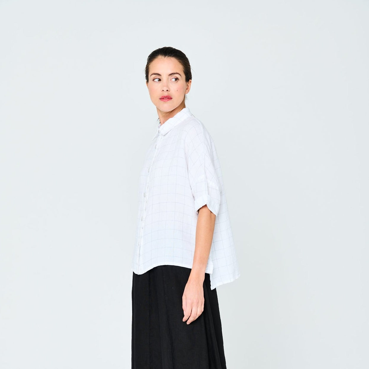 White linen shirt with a subtle grid pattern, oversized fit, and three-quarter sleeves.