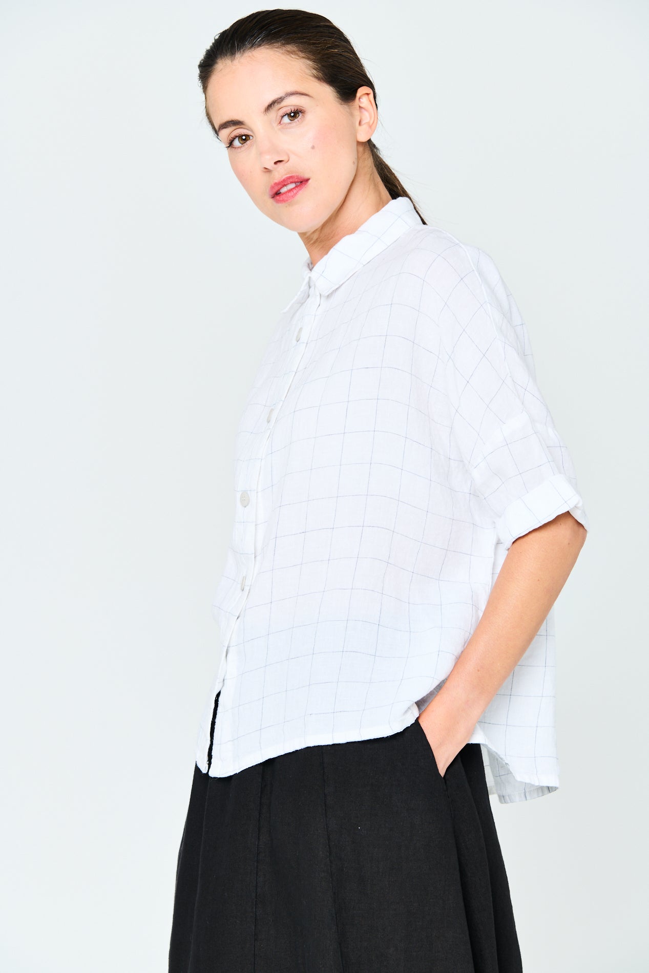 White linen shirt with a fine grid pattern, short sleeves, and a collared button-down front.