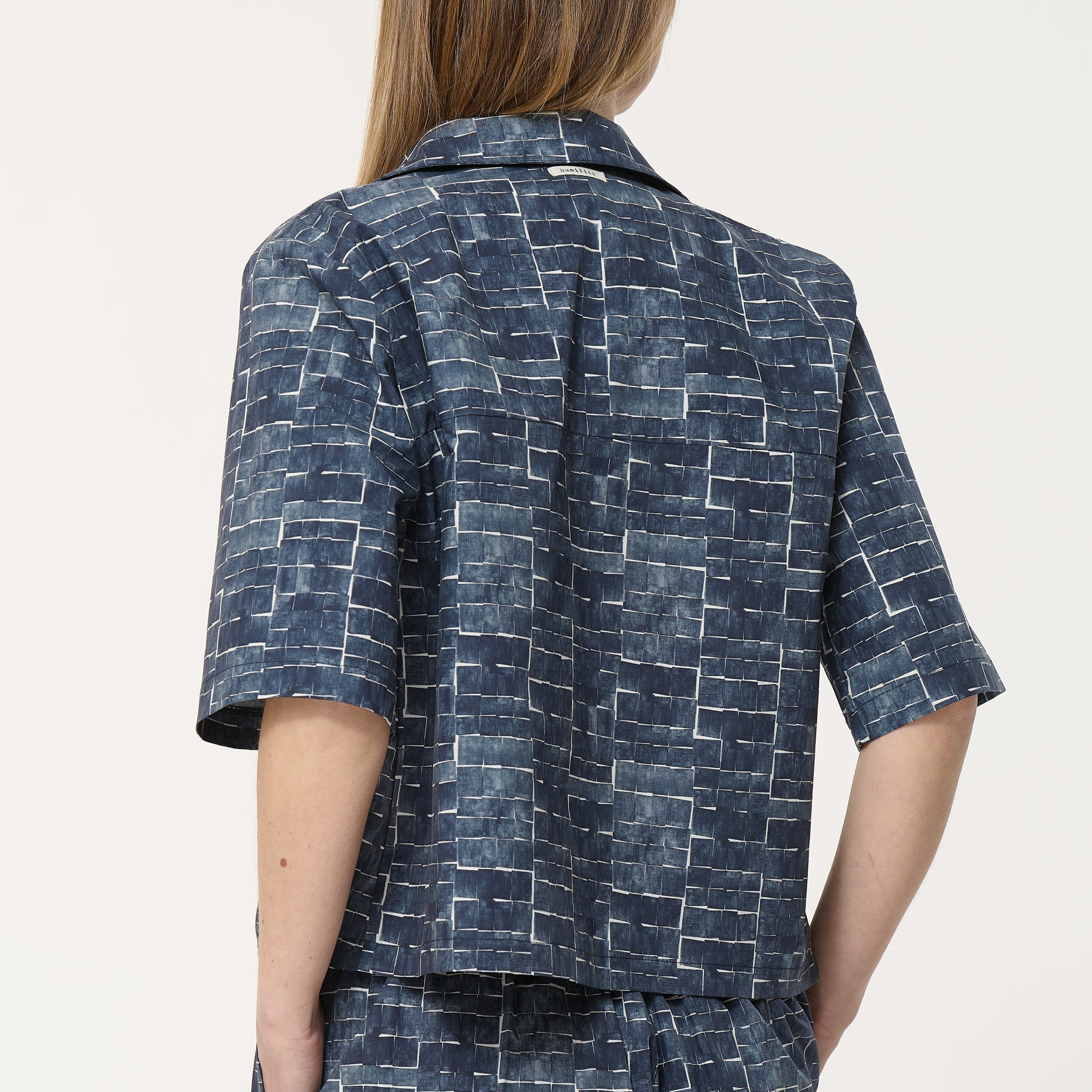 Women's short-sleeved collared shirt in navy blue with an abstract geometric print.  The shirt has a boxy fit.