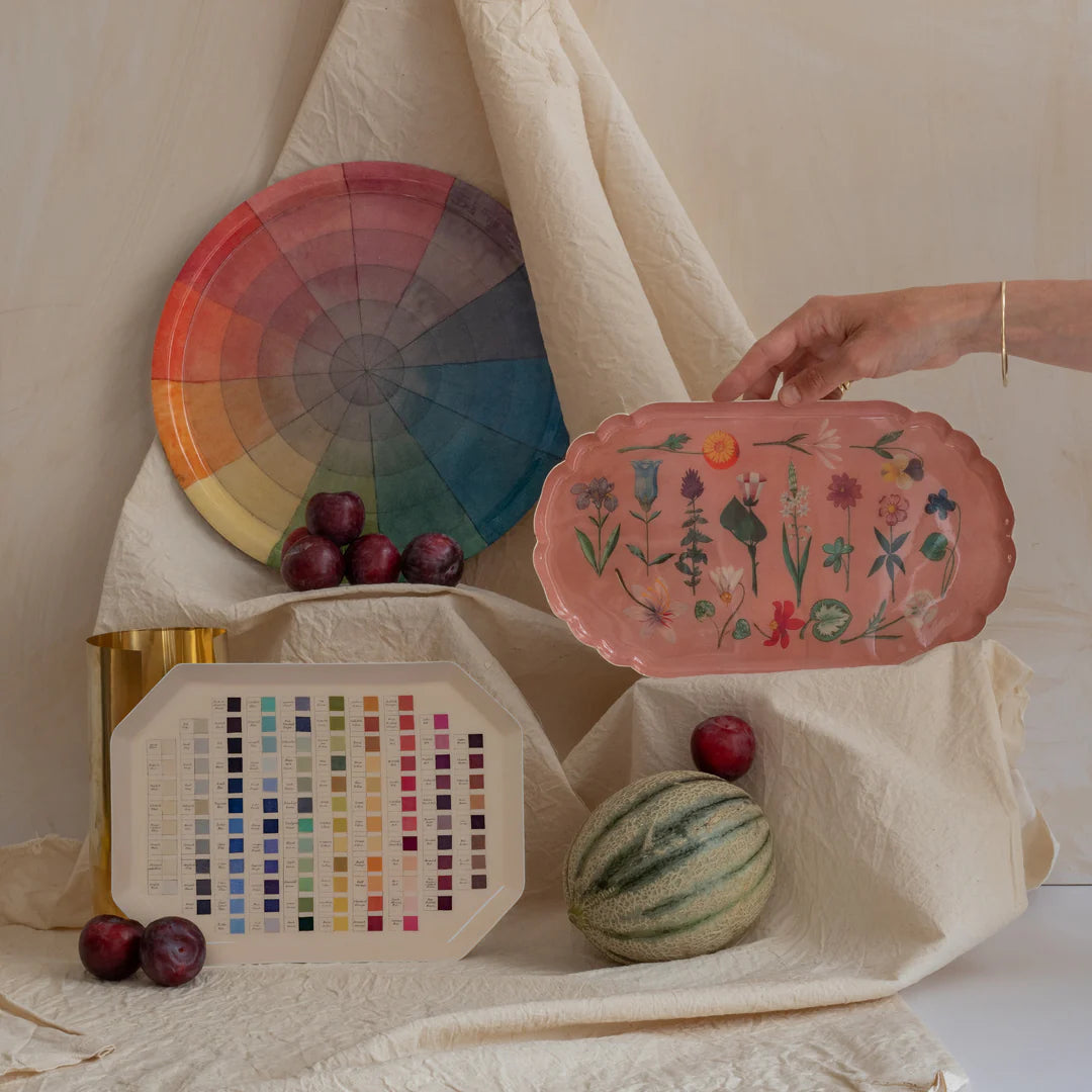 Decorative plates with floral designs, color swatches, and fruits on a neutral background