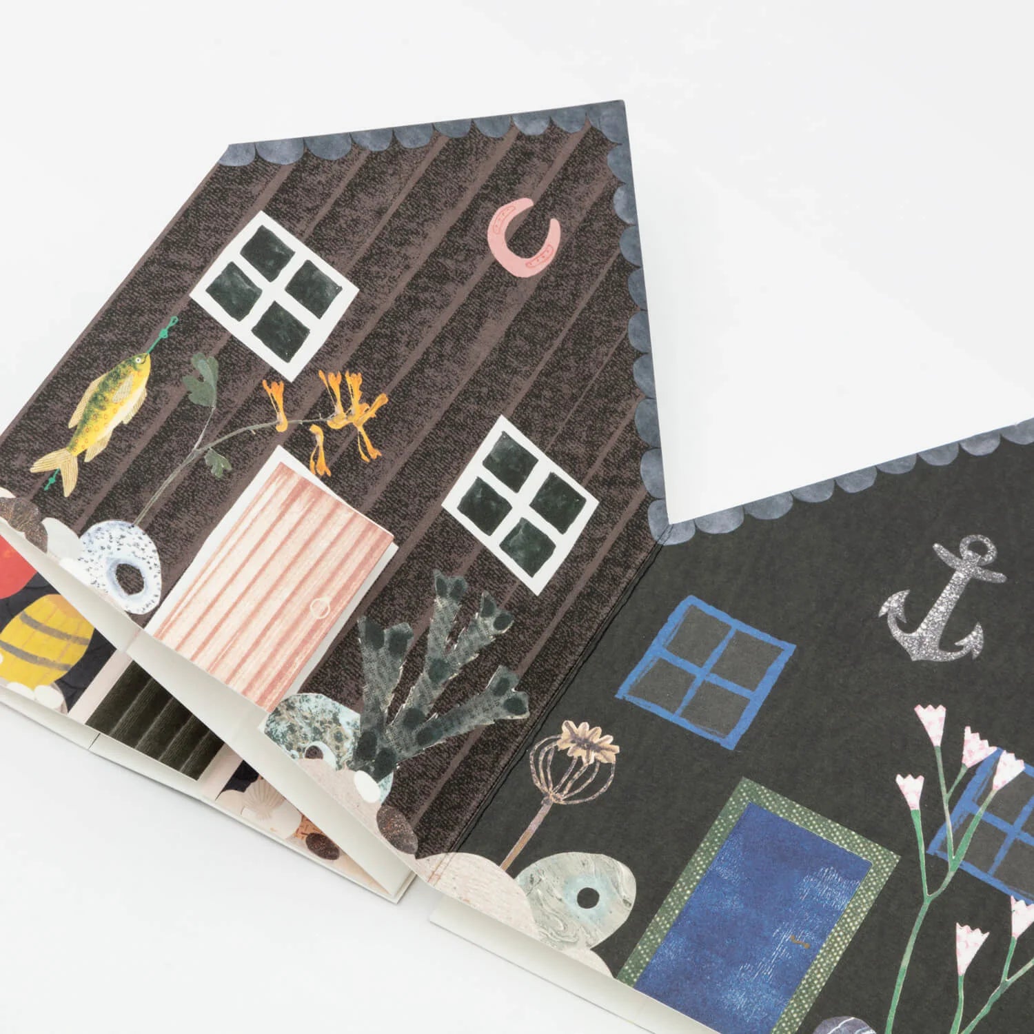 Folded paper house card featuring illustrated dark brown and black exterior, windows, doors, and nautical-themed details