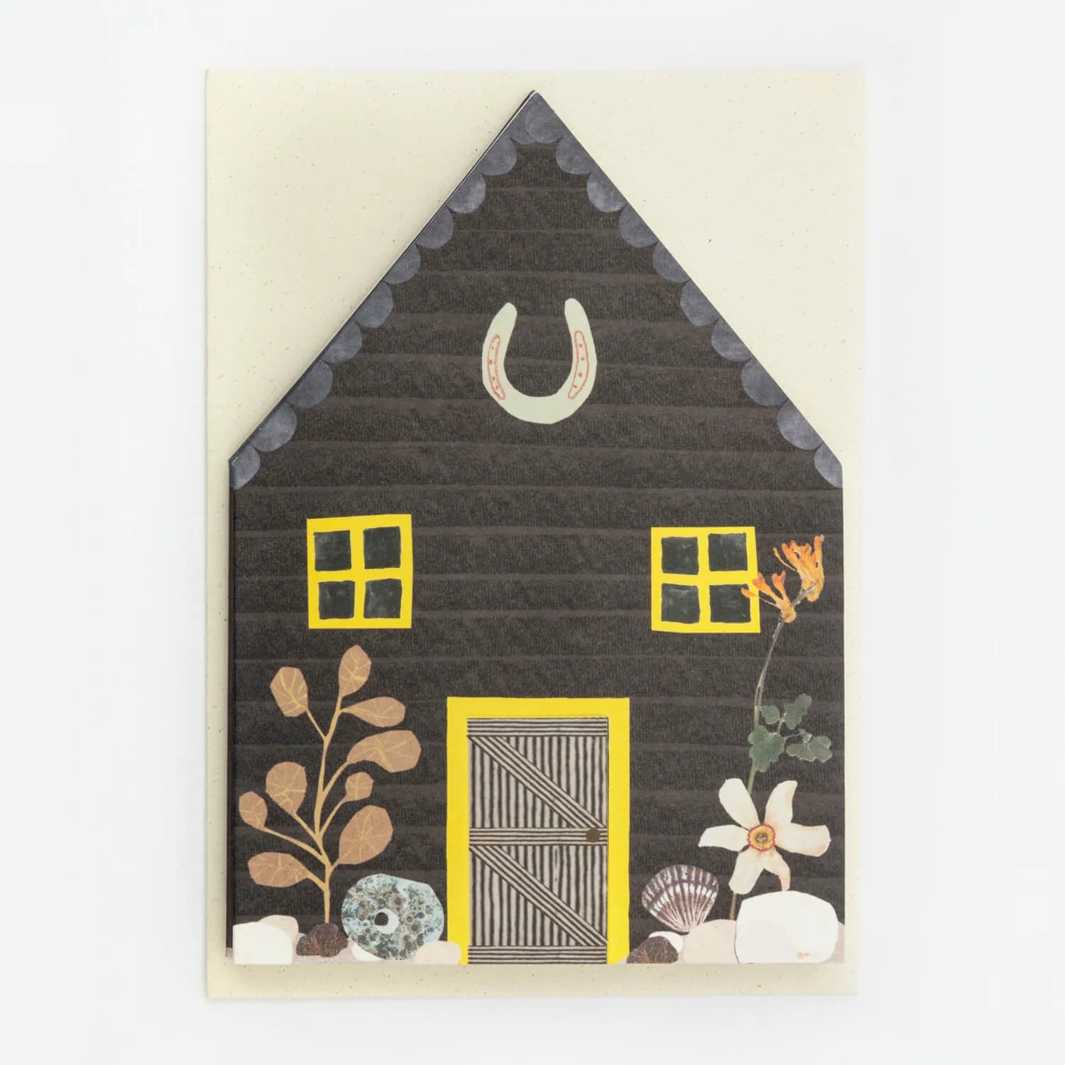 Dark gray house-shaped card with yellow windows and door, featuring a horseshoe and floral details.
