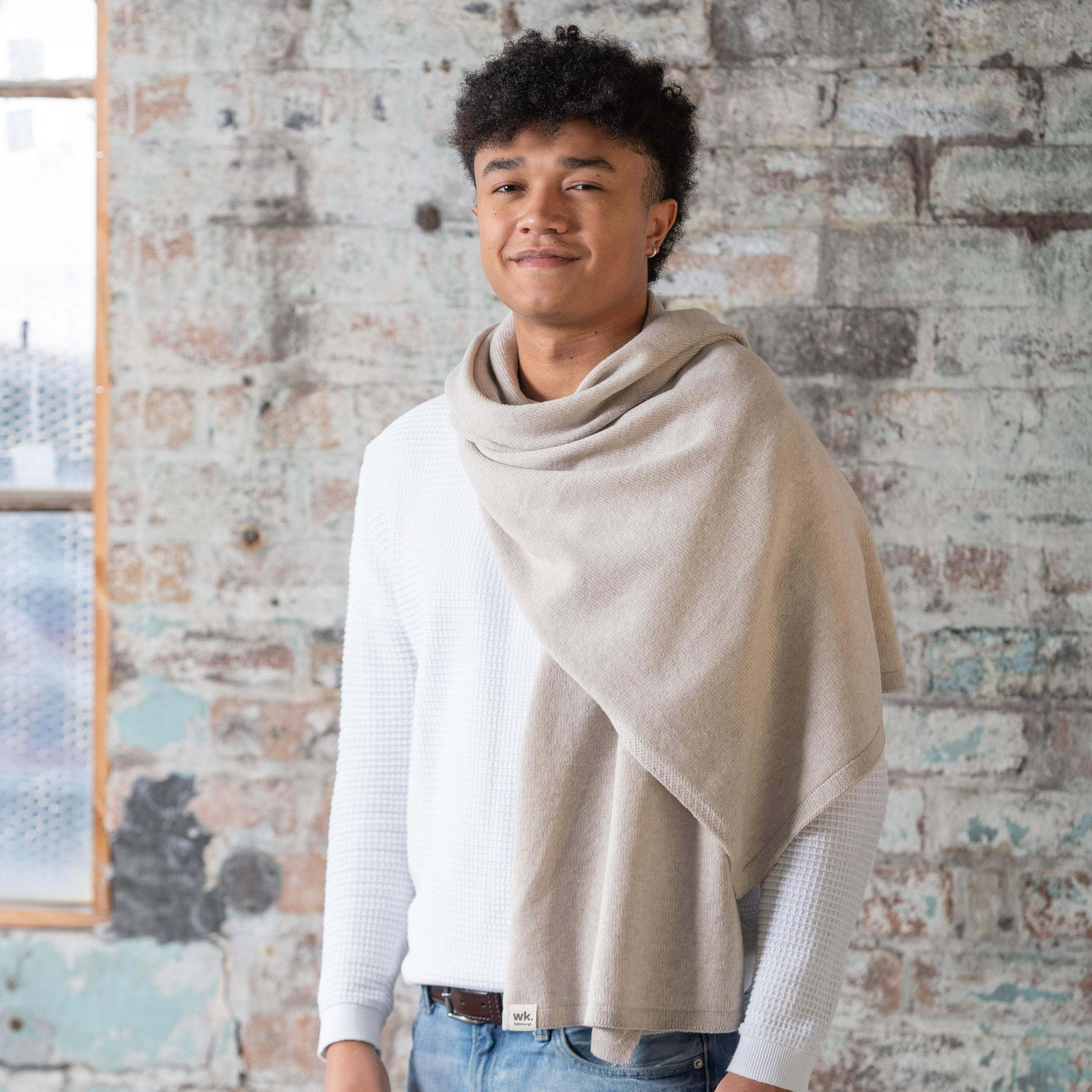 A light beige, loosely draped knit scarf.  The scarf has a subtle texture and a small woven label.