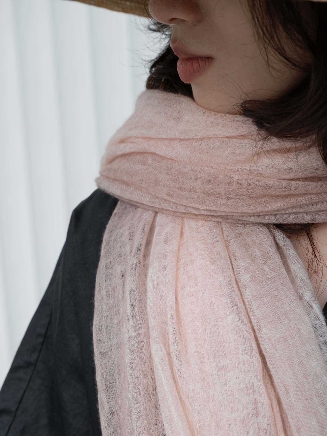 Person wearing a light pink scarf with a blurred background