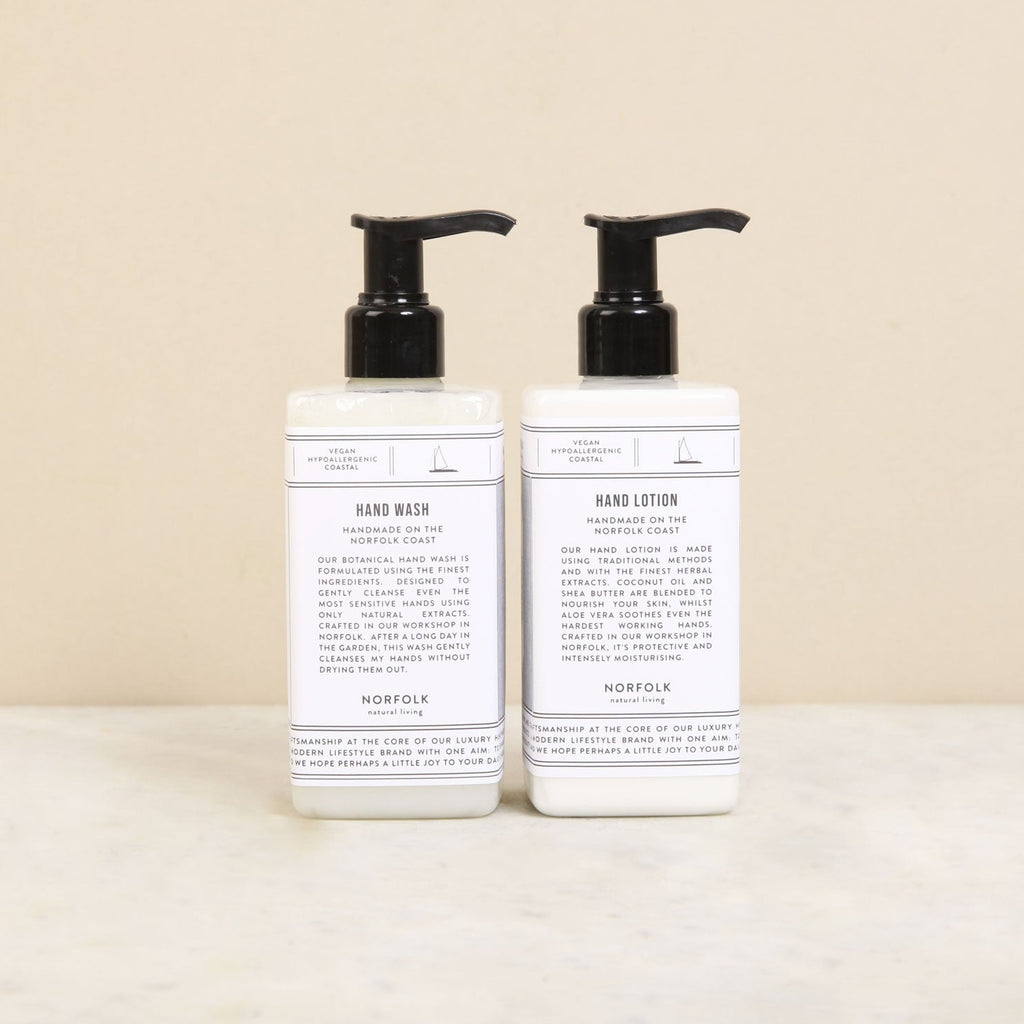 two black and white pump dispenser bottles, by Norfolk Natural Living, with black and white labels featuring product information on Hand Wash and Hand Lotion - Coastal Walks