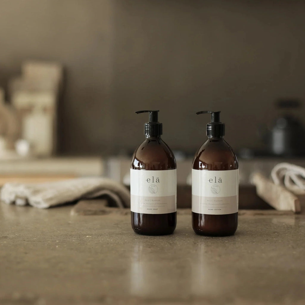 two amber glass, pump dispensing bottles, containing No. 2 / NURTURE Hand & Body Lotion, by Elä Life