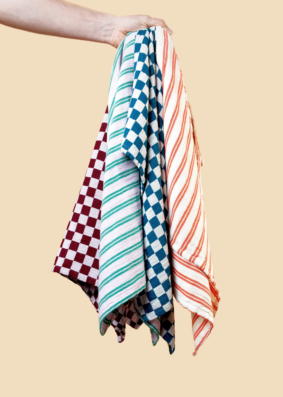 Colorful striped towel held by a person against a beige background