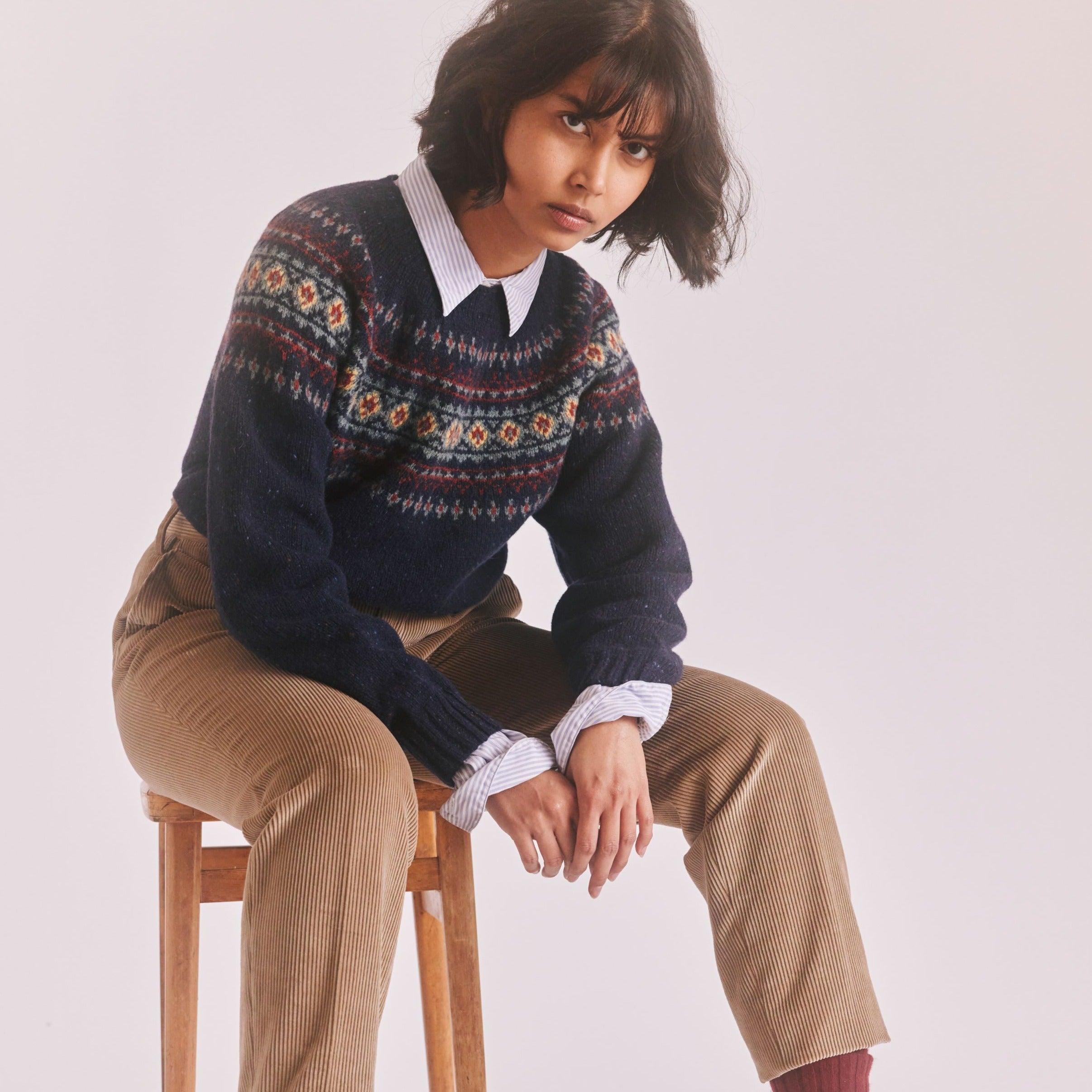 Dark navy blue wool sweater with a Fair Isle-style yoke featuring red, cream, and teal geometric patterns.
