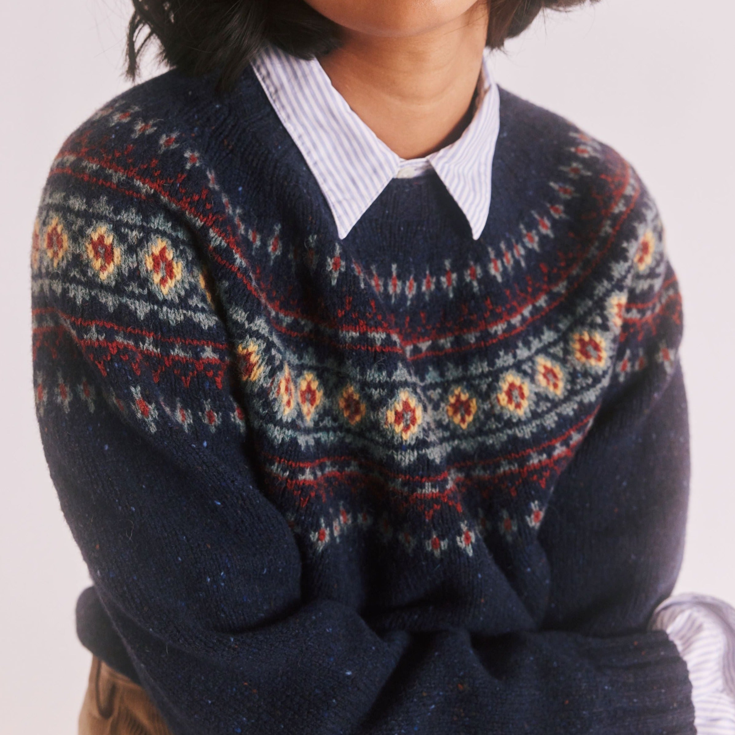 Navy blue crewneck sweater with a Fair Isle-style pattern in red, cream, and green.