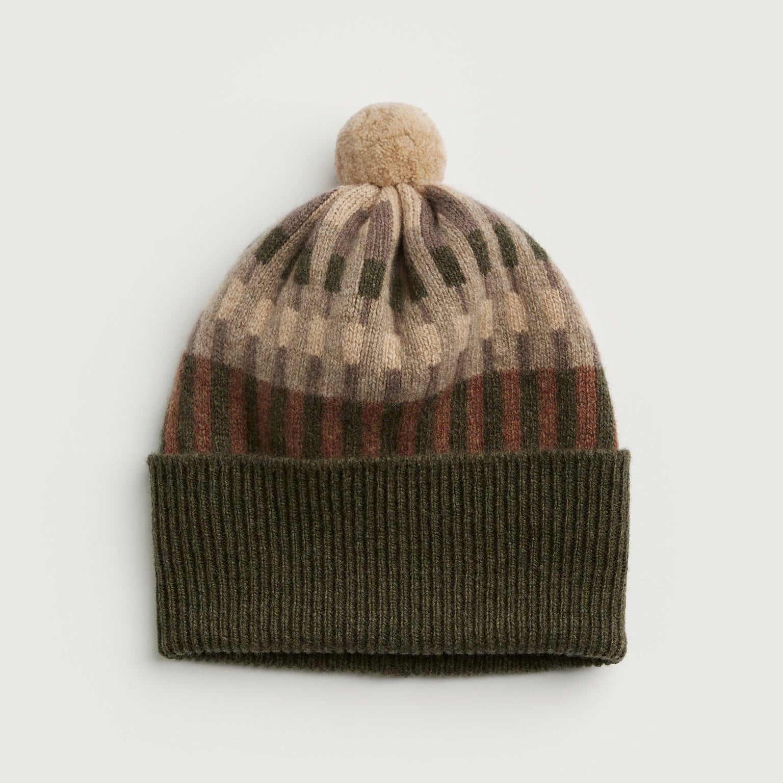 Knitted beanie with striped pattern and pom-pom on a light gray background